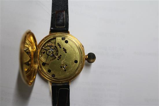 An 18ct gold half hunter wrist watch by Ashley & Sims, Clerkenwell, on leather strap.